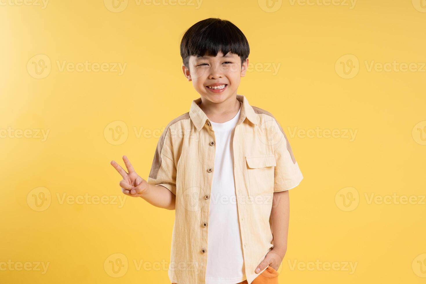 Portrait of adorable asian boy posing on yellow background photo