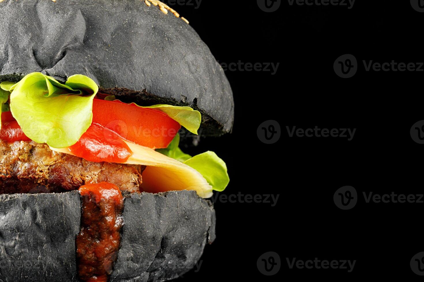 Black burger close-up. Burger with tomatoes, greens, onions and meat. place for text cope space photo