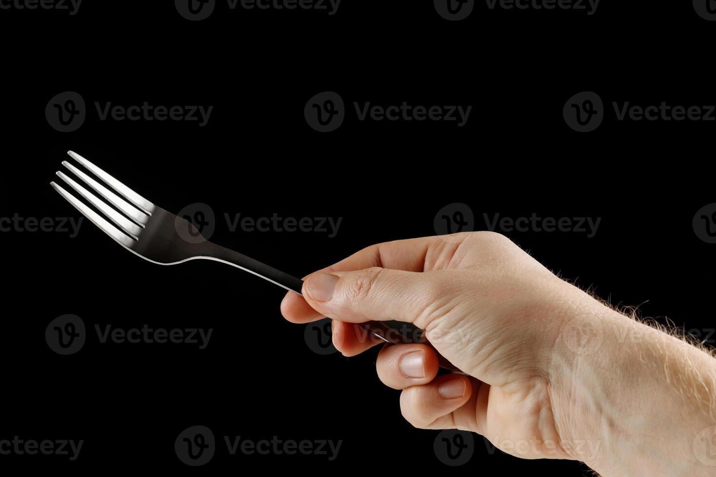 Fork in hand isolate on black photo