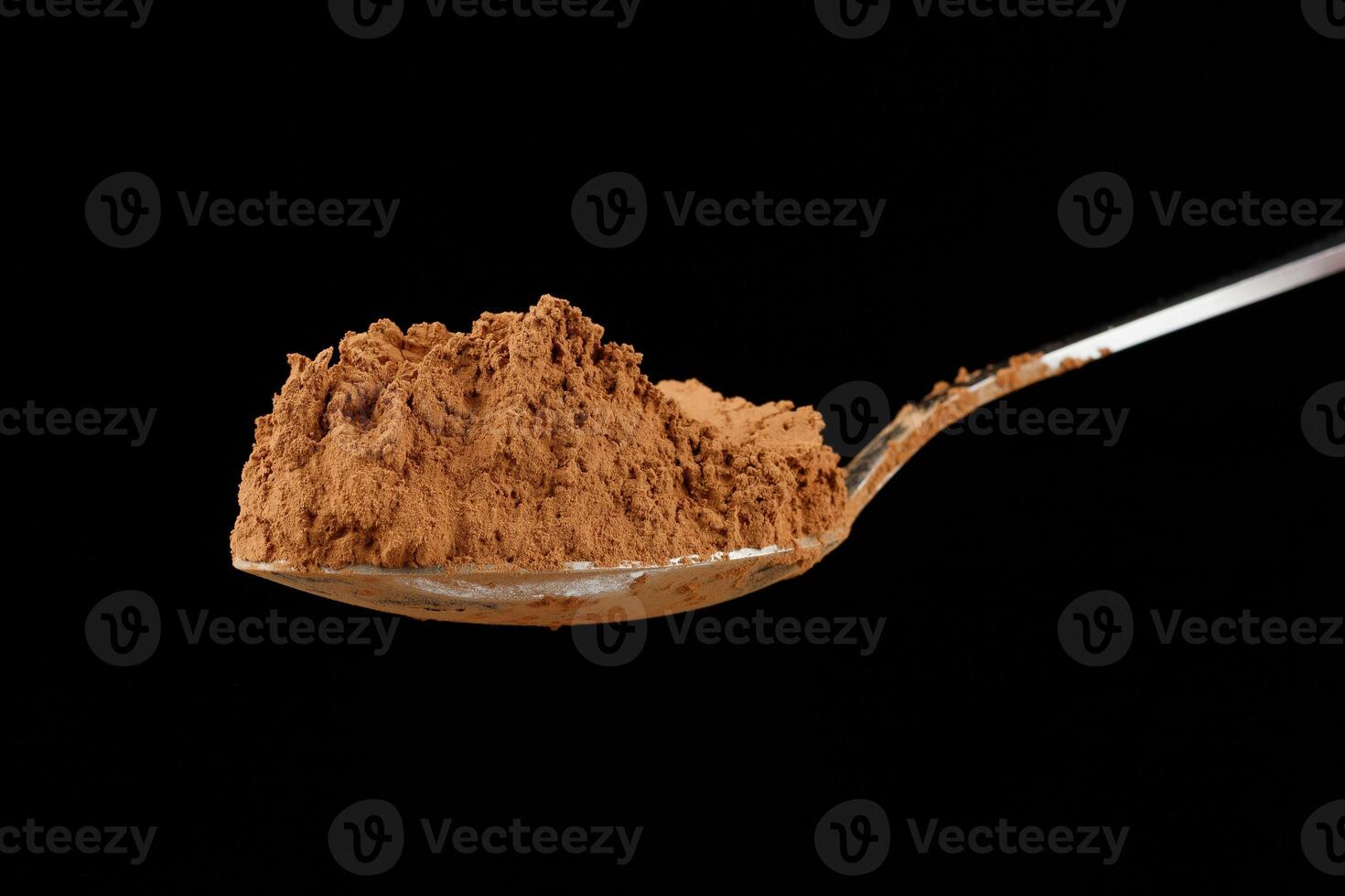 Cocoa powder on a spoon on black close-up photo
