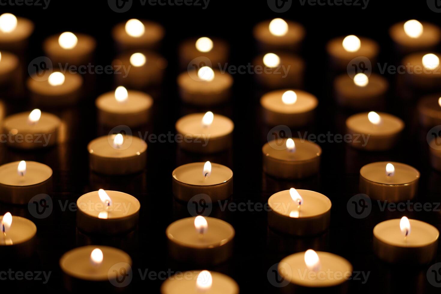 Many candle flames glowing on dark background. candles in memory of the dead photo