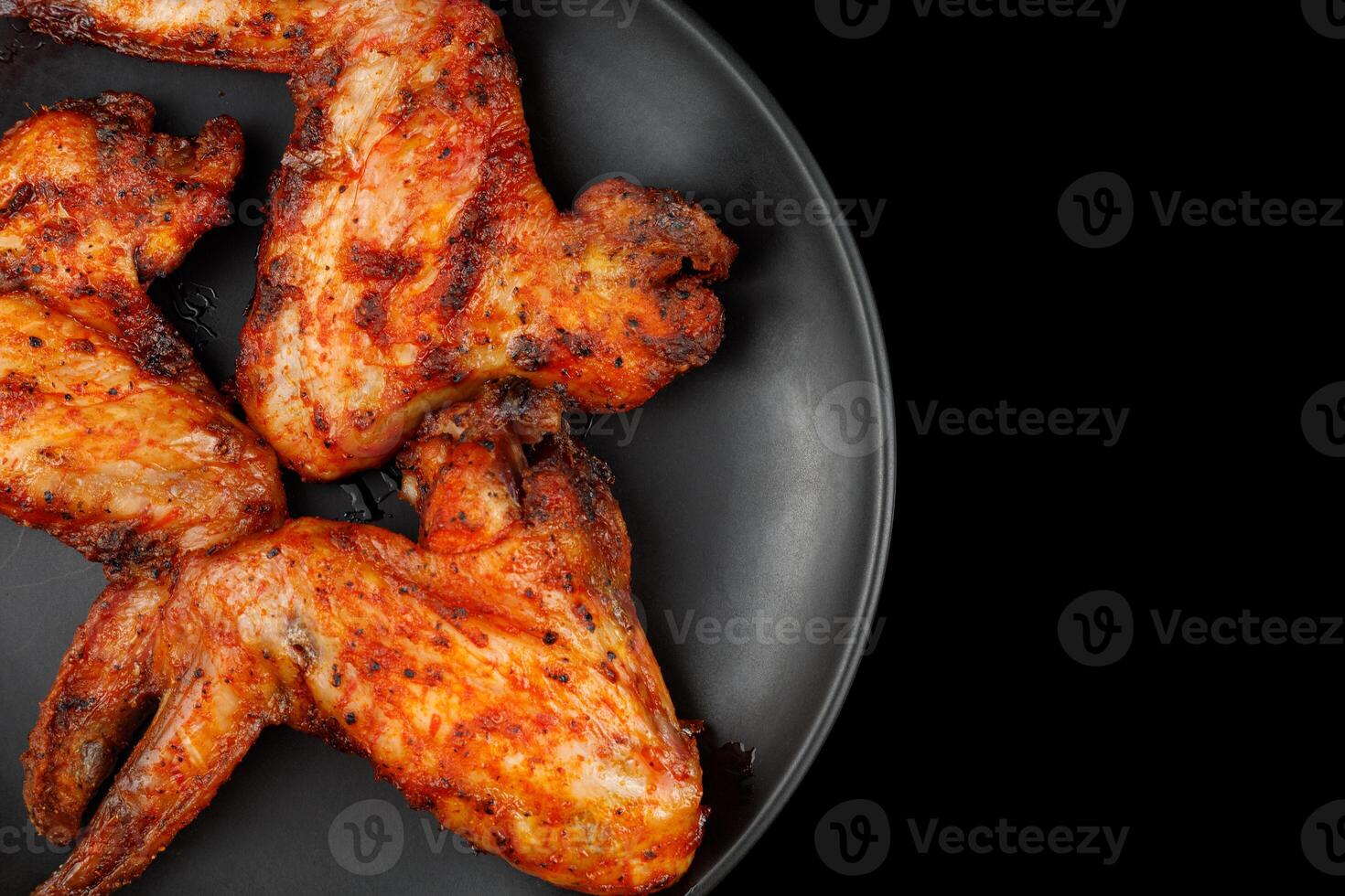 Fried chicken wings on a black plate. BBQ Chicken Wings photo