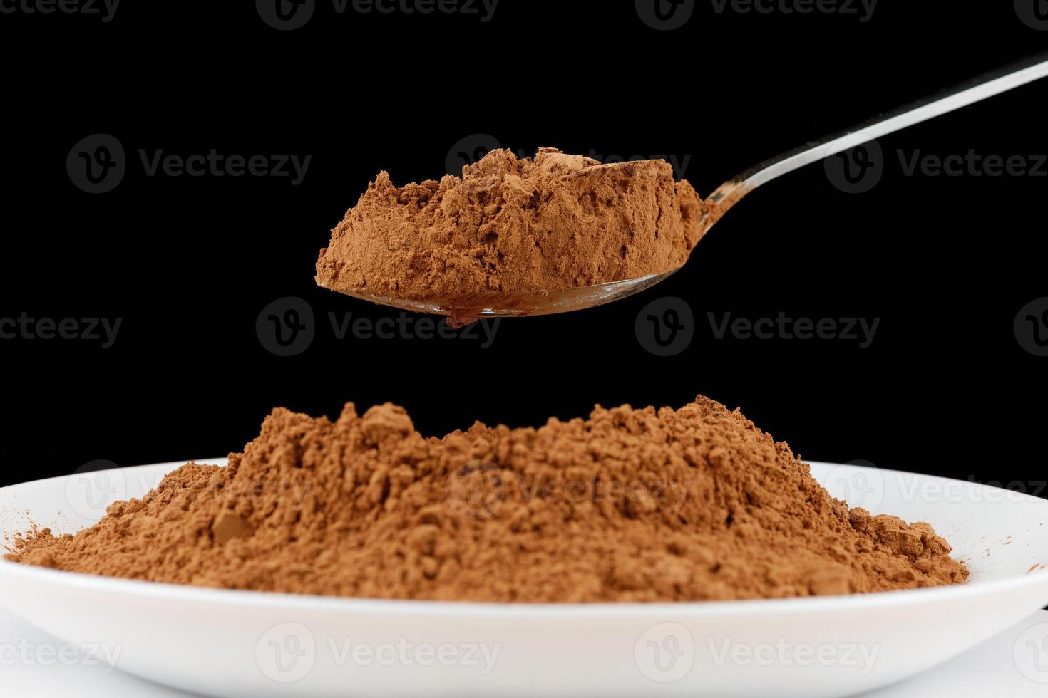 Cocoa powder on a spoon on black close-up photo