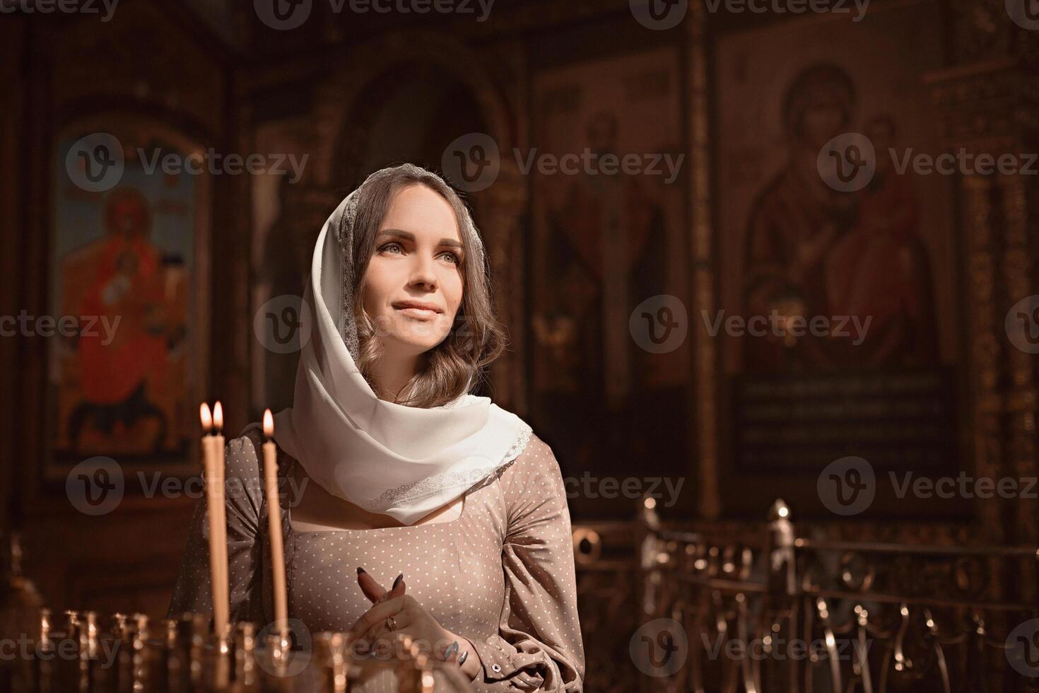 Young beautiful woman in the Orthodox Church lit candles in a candlestick photo