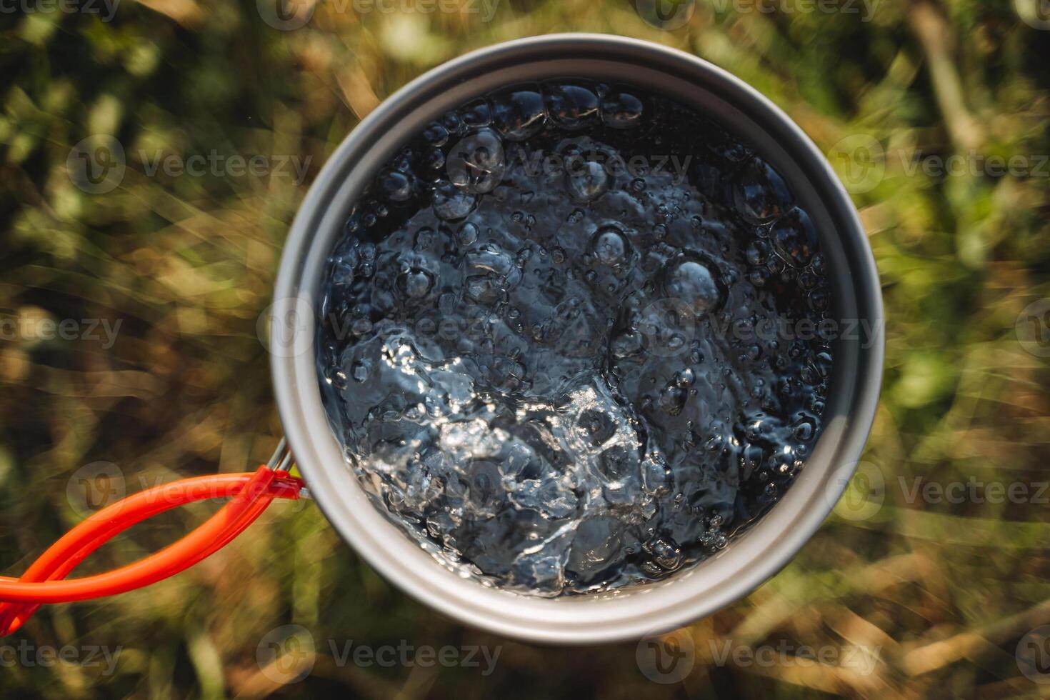 Boil water in a pot in nature, hike in the forest cooking on a gas burner, cook soup, warm tea, bubbling water. photo