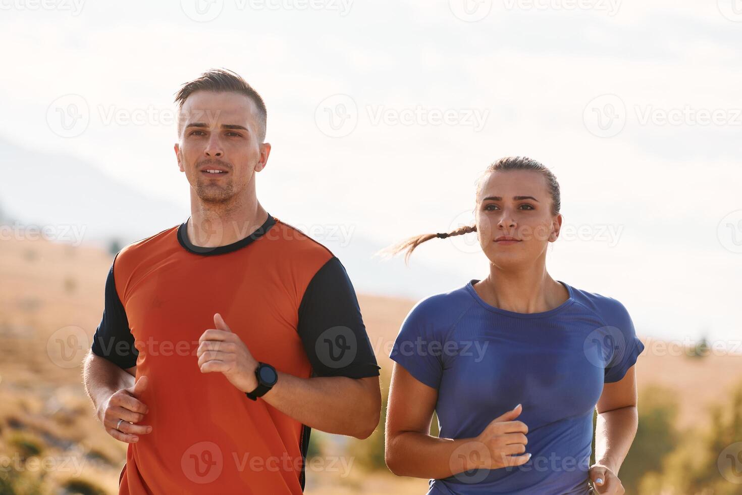 A couple dressed in sportswear runs along a scenic road during an early morning workout, enjoying the fresh air and maintaining a healthy lifestyle photo