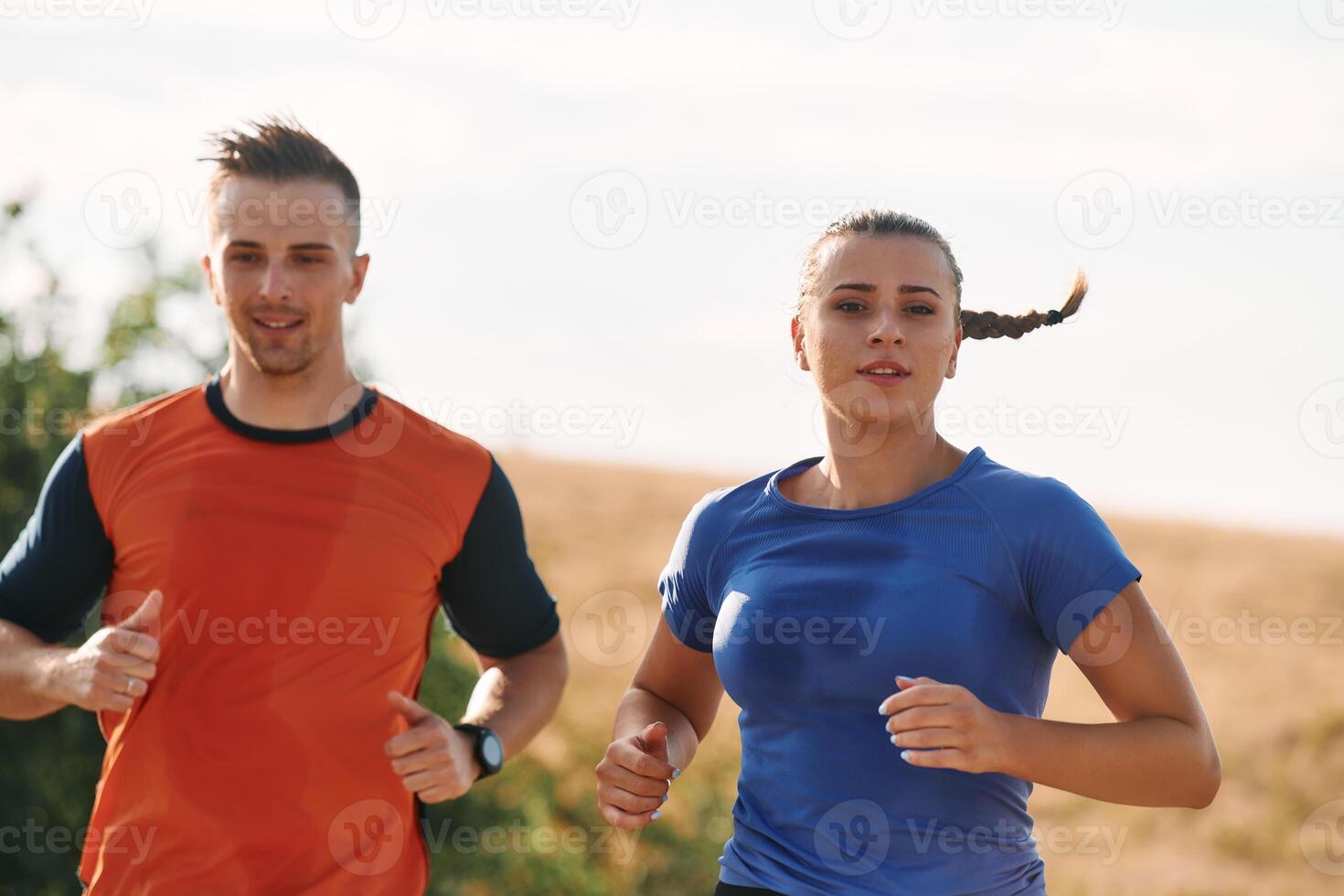 A couple dressed in sportswear runs along a scenic road during an early morning workout, enjoying the fresh air and maintaining a healthy lifestyle photo