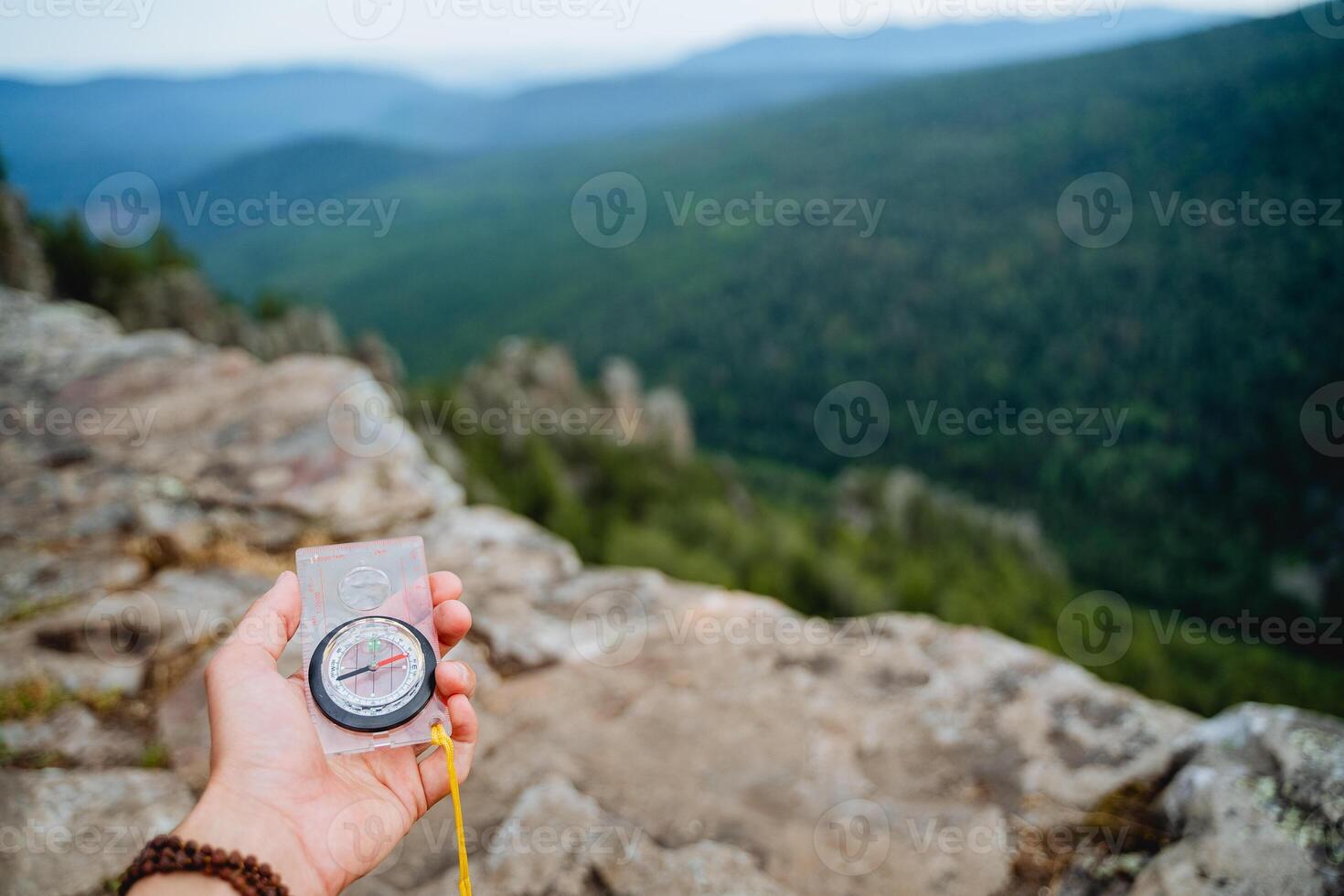 orienteering, compass in the hand, mountainous terrain, search for a route in a hike, direction of movement along the azimuth. photo