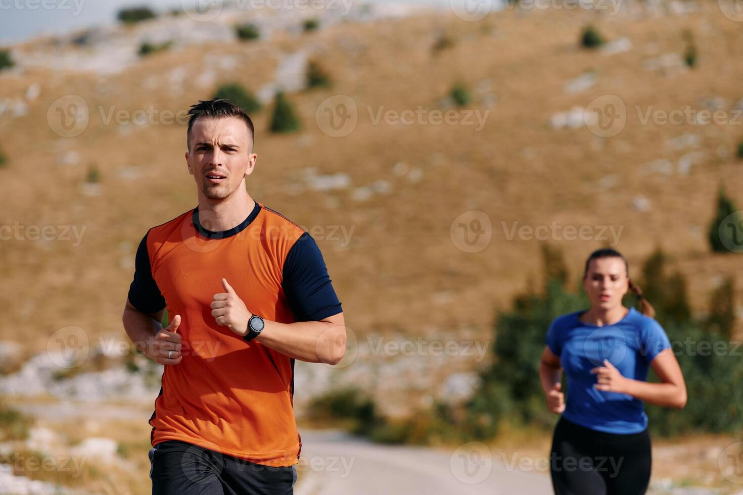 A couple dressed in sportswear runs along a scenic road during an early morning workout, enjoying the fresh air and maintaining a healthy lifestyle photo