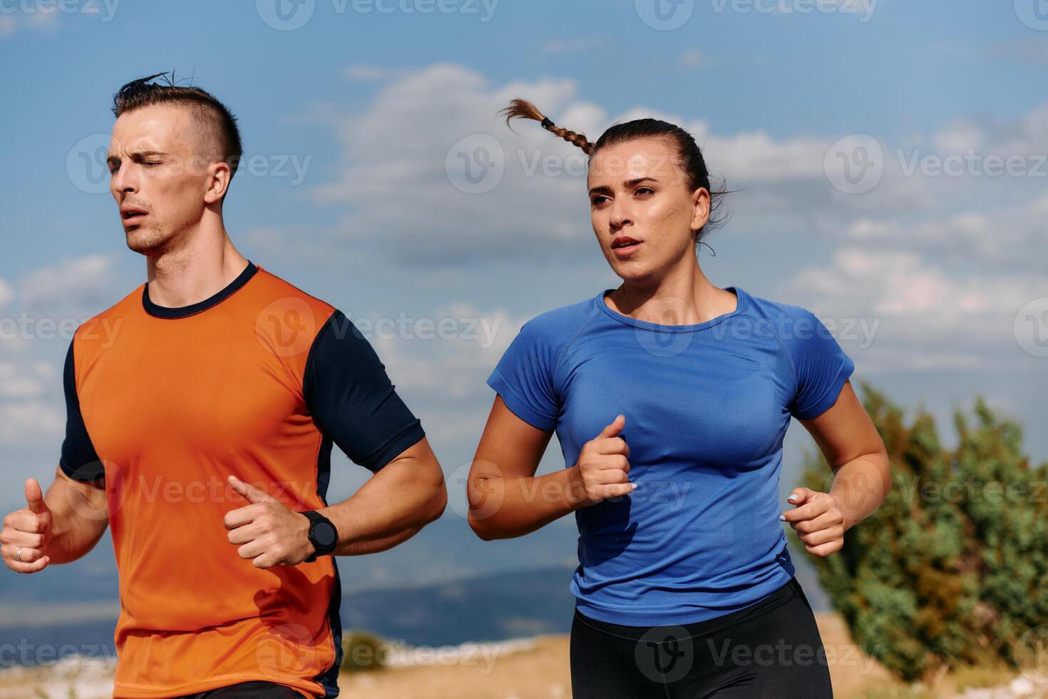 A couple dressed in sportswear runs along a scenic road during an early morning workout, enjoying the fresh air and maintaining a healthy lifestyle photo
