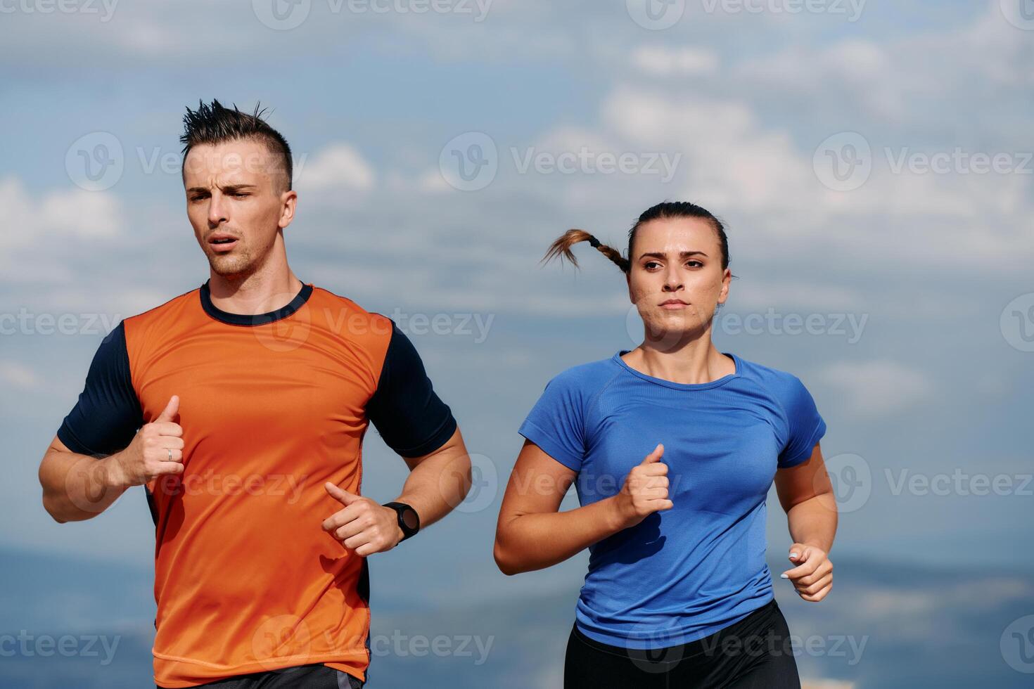 A couple dressed in sportswear runs along a scenic road during an early morning workout, enjoying the fresh air and maintaining a healthy lifestyle photo