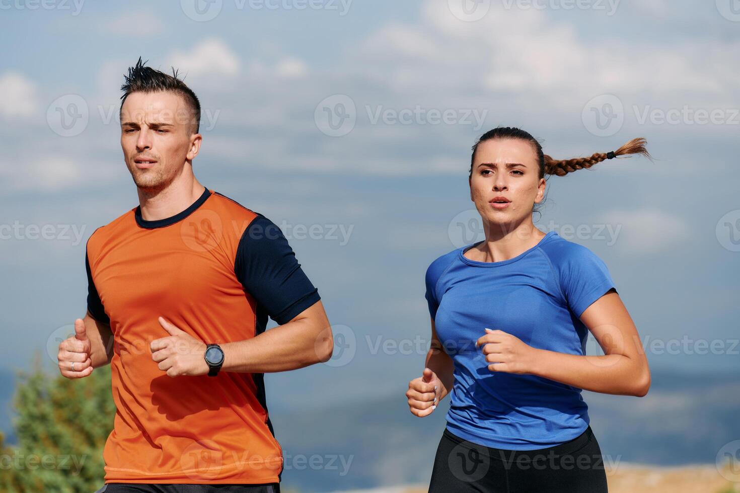 A couple dressed in sportswear runs along a scenic road during an early morning workout, enjoying the fresh air and maintaining a healthy lifestyle photo