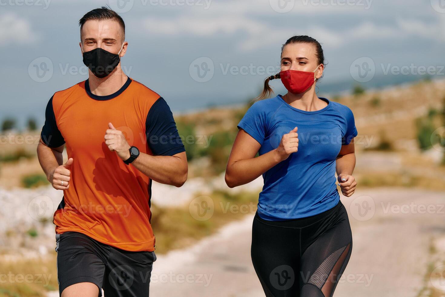 Couple running in nature at morning wearing protective face masks photo