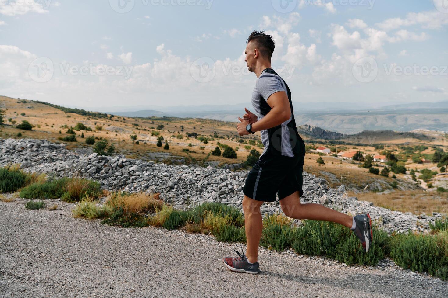 Determined Athlete Running Through Rugged Mountain Terrain at Sunrise. photo