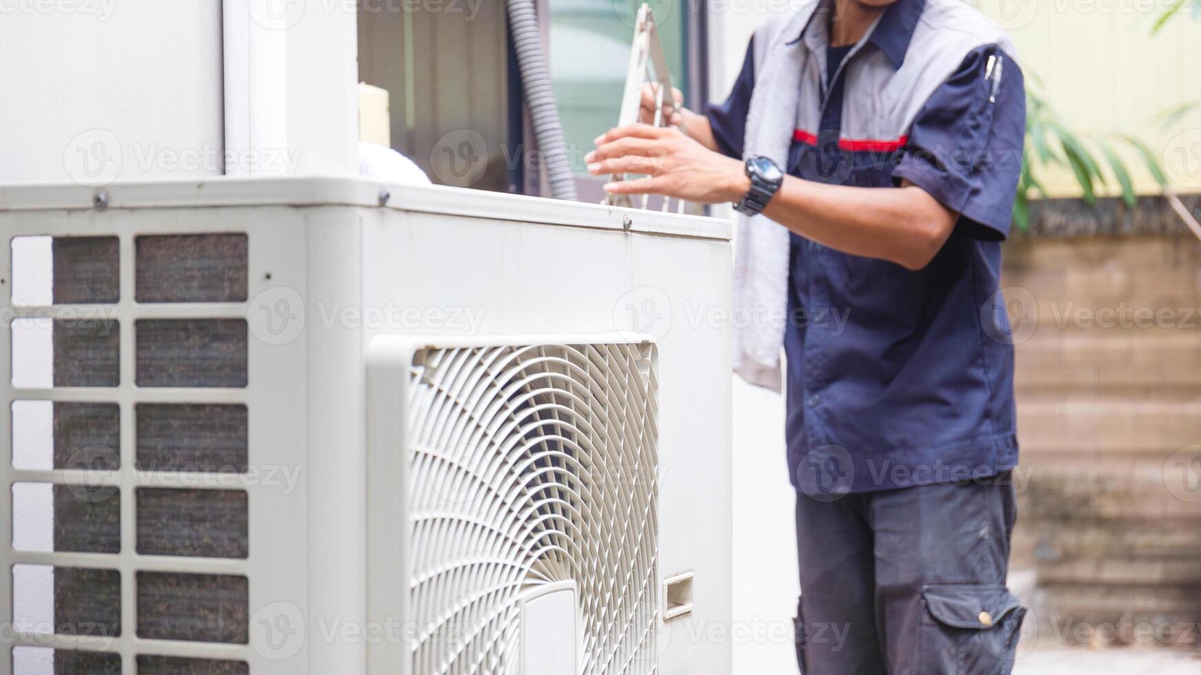 Selective focus of Air conditioner compressor with blurred technician man cleaning air conditioner in background, Repairman washing dirty compartments air conditioner photo