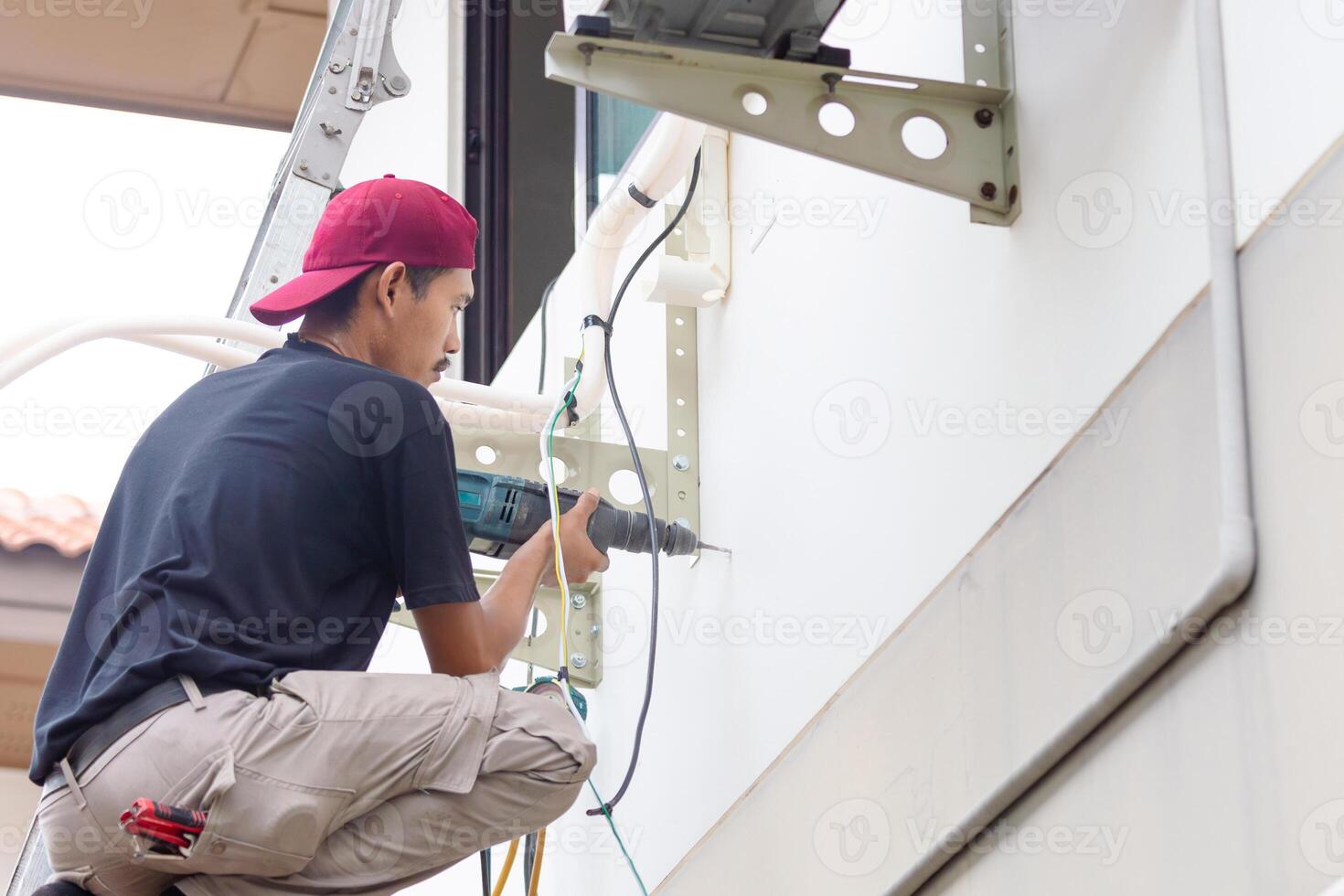 Technician man with hammer drill installing an air conditioning, Repairman service for repair and maintenance of air conditioners photo