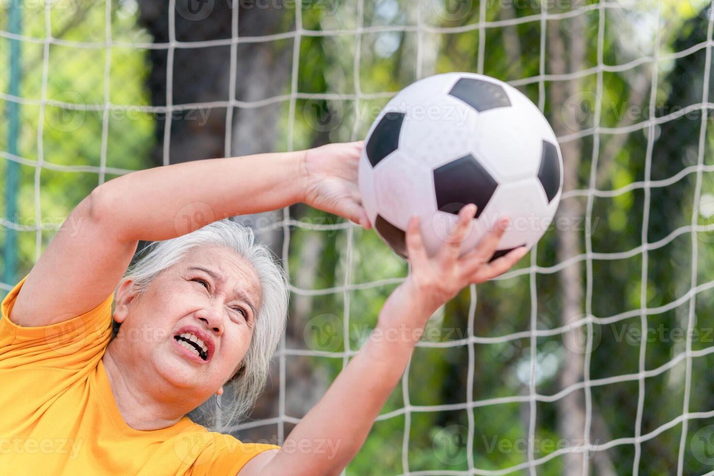 Active senior woman playing football in the urban outdoor court, Asian senior woman with a soccer ball, Healthy life concepts photo