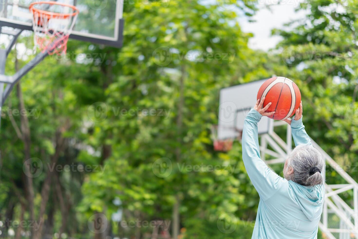 Active senior woman playing basketball in the urban outdoor basketball court, healthy life concepts photo