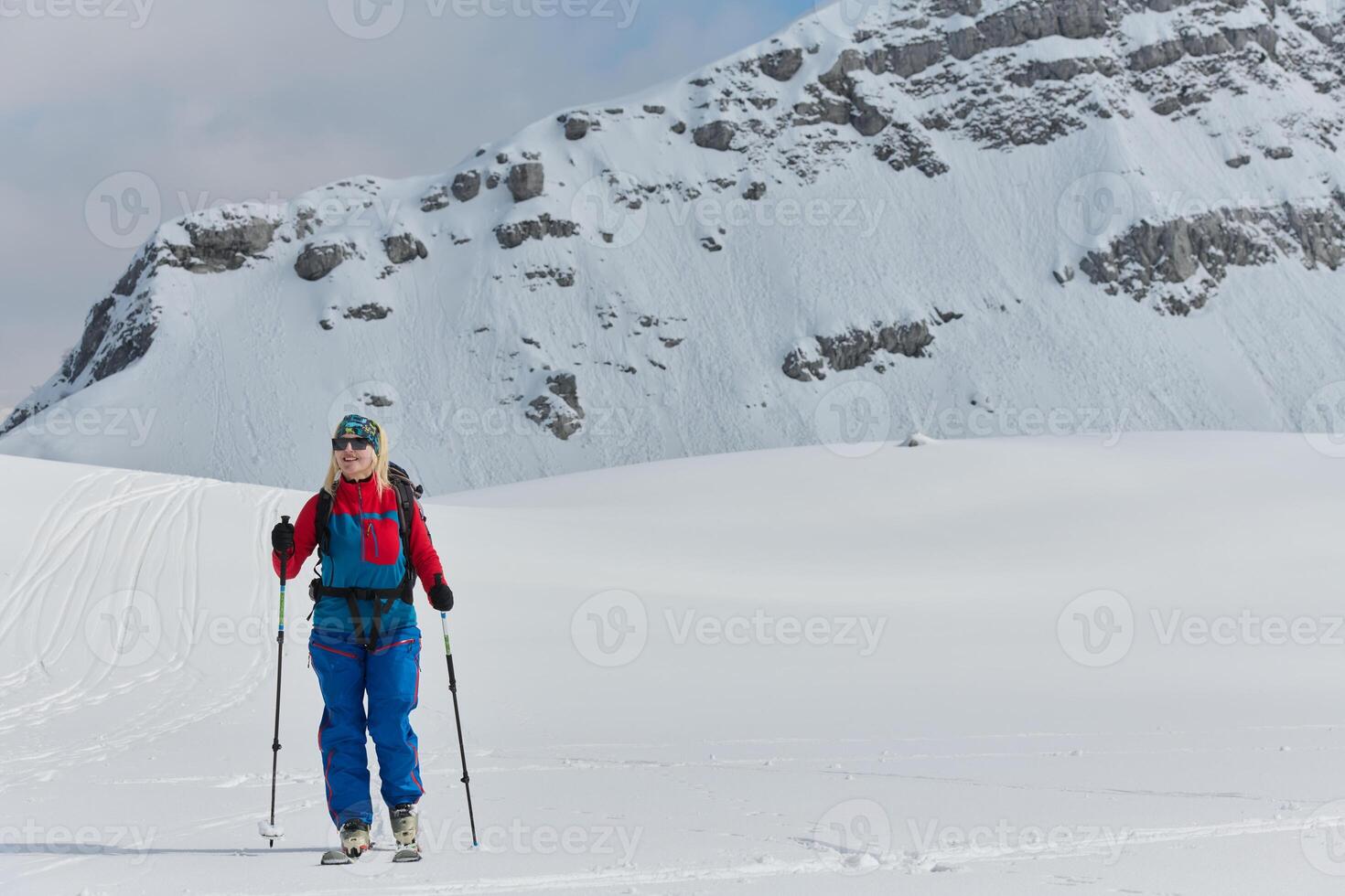 A professional woman skier rejoices after successfully climbing the snowy peaks of the Alps photo