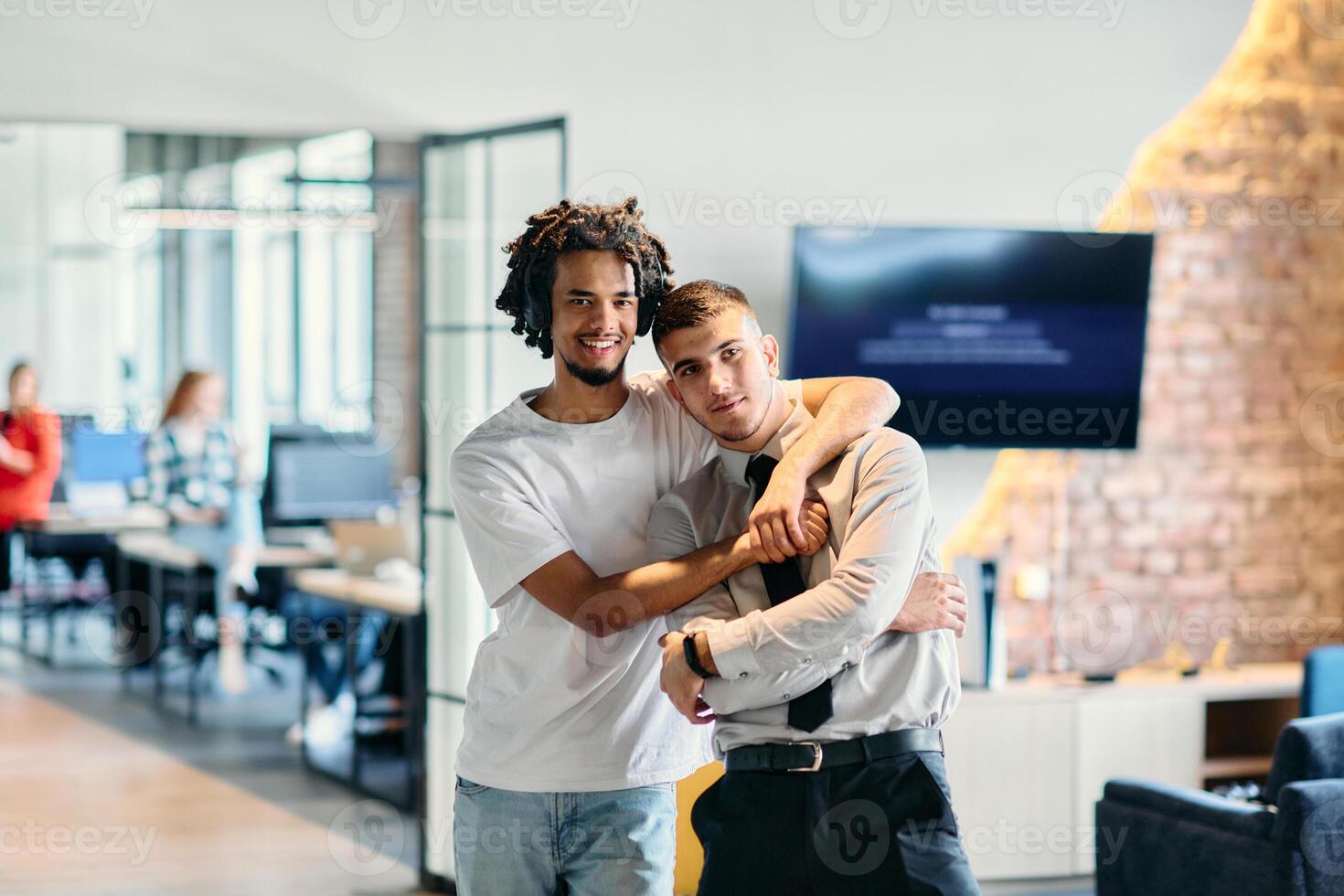 A group of colleagues, including an African American businessman and a young leader in a shirt and tie, pose together in a modern coworking center office, representing a dynamic blend of photo