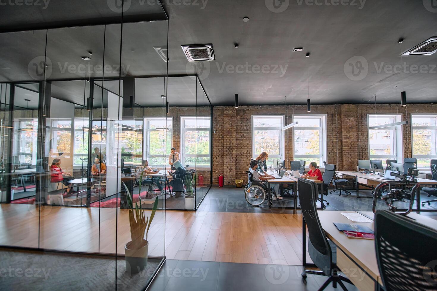 A diverse group of business professionals collaborates in a modern startup coworking center, utilizing a mix of paper-based and technological tools such as mobile phones and computers photo