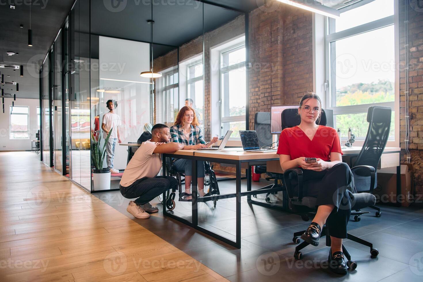A diverse group of business professionals collaborates in a modern startup coworking center, utilizing a mix of paper-based and technological tools such as mobile phones and computers photo