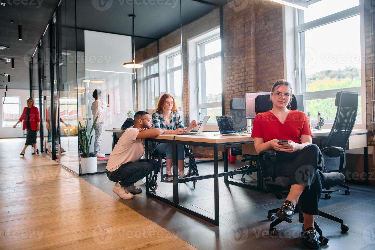 A diverse group of business professionals collaborates in a modern startup coworking center, utilizing a mix of paper-based and technological tools such as mobile phones and computers photo