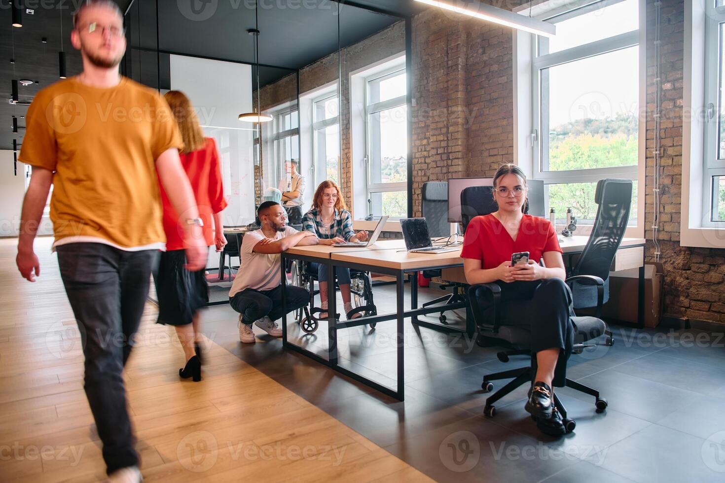 A diverse group of business professionals collaborates in a modern startup coworking center, utilizing a mix of paper-based and technological tools such as mobile phones and computers photo