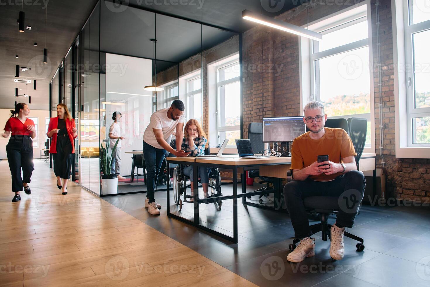 A diverse group of business professionals collaborates in a modern startup coworking center, utilizing a mix of paper-based and technological tools such as mobile phones and computers to collectively photo