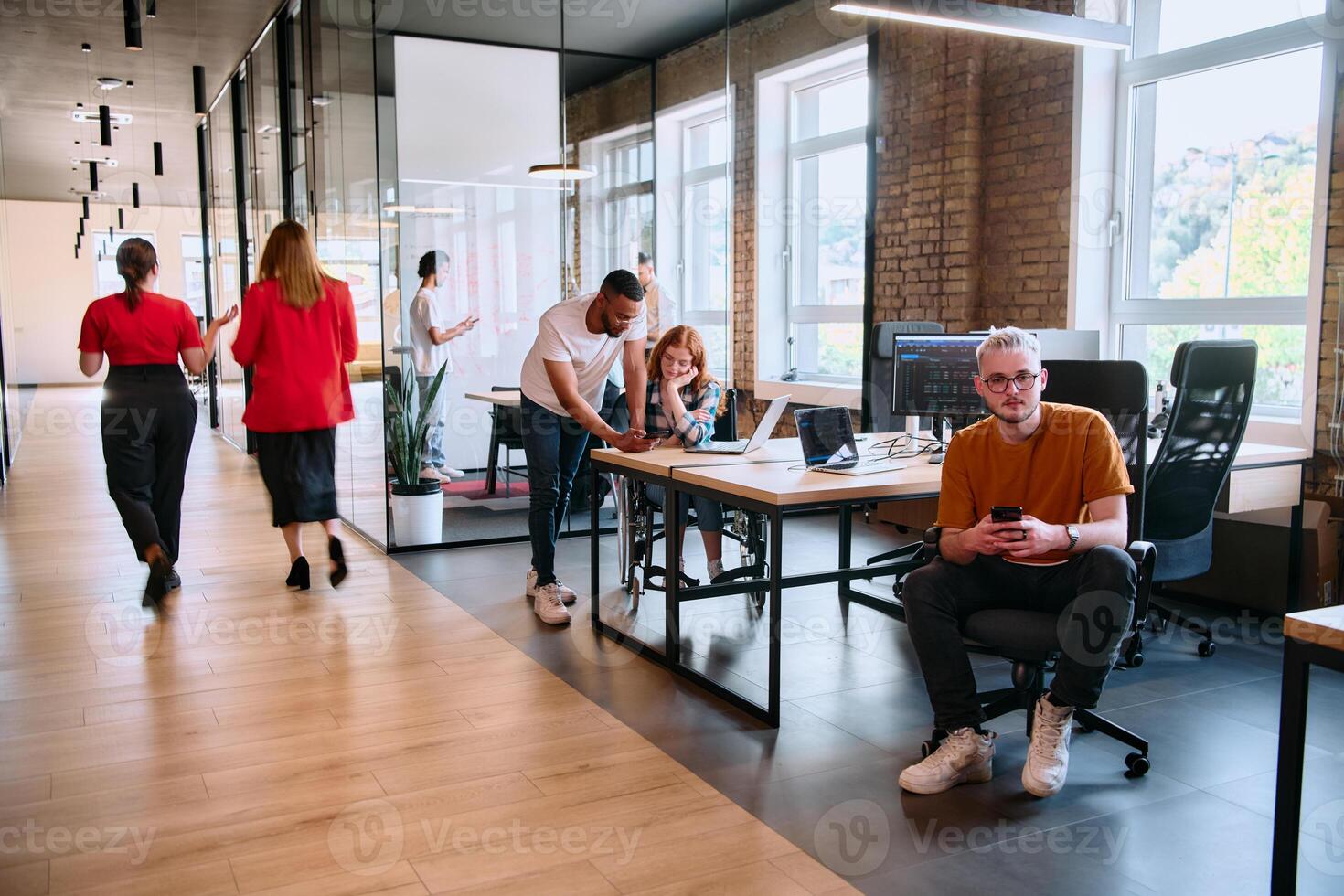 A diverse group of business professionals collaborates in a modern startup coworking center, utilizing a mix of paper-based and technological tools such as mobile phones and computers photo