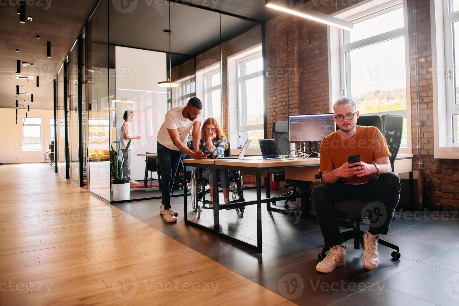 A diverse group of business professionals collaborates in a modern startup coworking center, utilizing a mix of paper-based and technological tools such as mobile phones and computers photo
