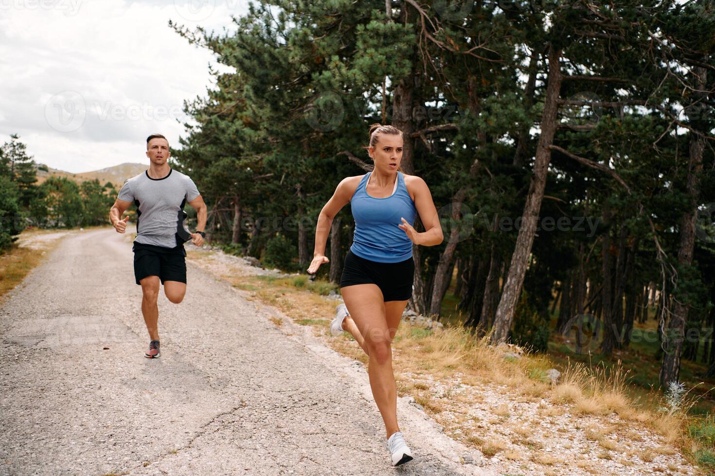A couple dressed in sportswear runs along a scenic road during an early morning workout, enjoying the fresh air and maintaining a healthy lifestyle photo