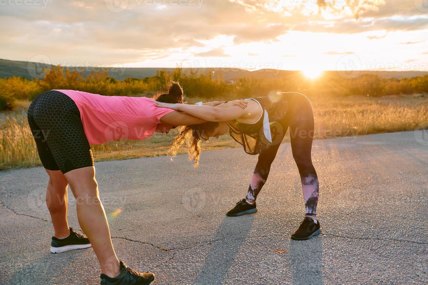 Two Women Athletes Stretching at Sunset in Beautiful Natural Surroundings photo