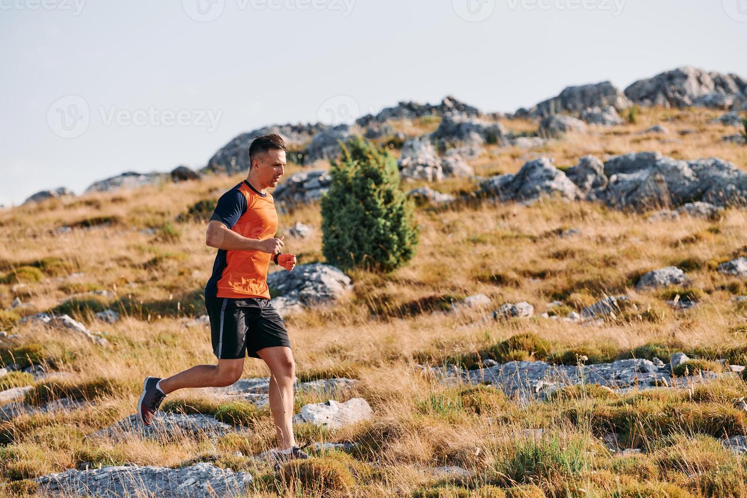 Determined Athlete Running Through Rugged Mountain Terrain at Sunrise. photo