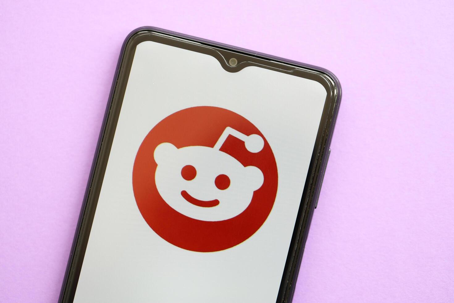 KYIV, UKRAINE - APRIL 1, 2024 Reddit icon on smartphone screen on purple table photo