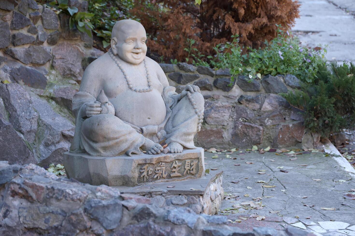 Cherkasy, UKRAINE - OCTOBER 20, 2021 Joyful Buddah concrete grey statue close to White Lotus buddhist temple photo