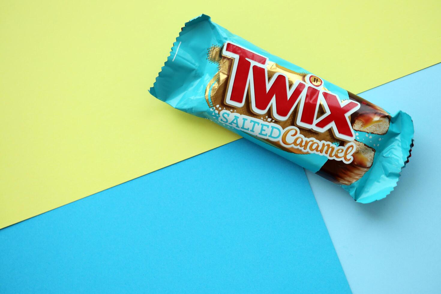 TERNOPIL, UKRAINE - JULY 7, 2023 Twix salted caramel blue wrapper on wooden background. Twix is a chocolate bar made by Mars Inc consisting of biscuit applied with caramel photo