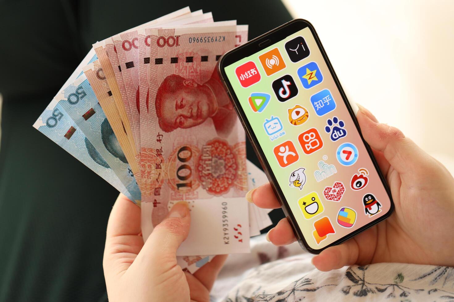 KYIV, UKRAINE - APRIL 1, 2024 Asian apps icon on smartphone screen and money in female hand photo