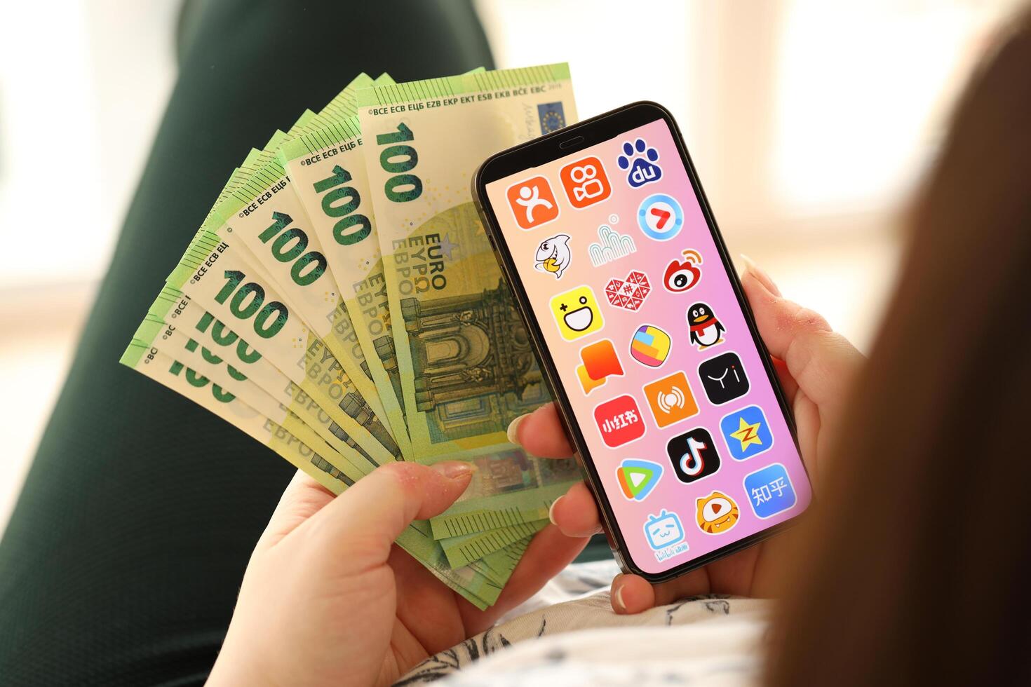 KYIV, UKRAINE - APRIL 1, 2024 Asian apps icon on smartphone screen and money in female hand photo