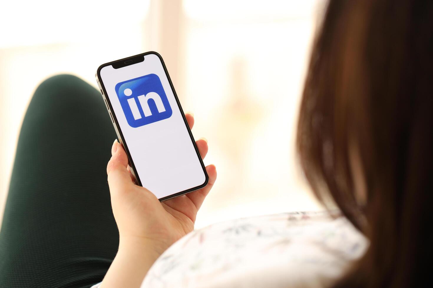 KYIV, UKRAINE - APRIL 1, 2024 LinkedIn icon on smartphone screen in young female hands photo