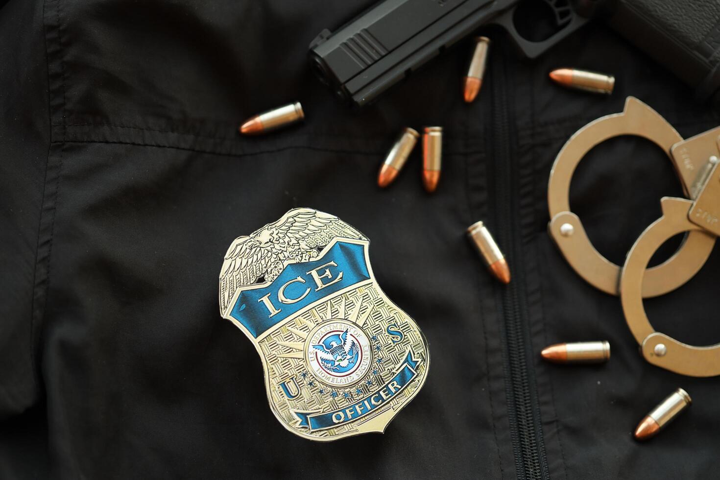 KYIV, UKRAINE - MARCH 9, 2024 US ICE Officer badge on black jacket uniform with gun, bullets and handcuffs photo