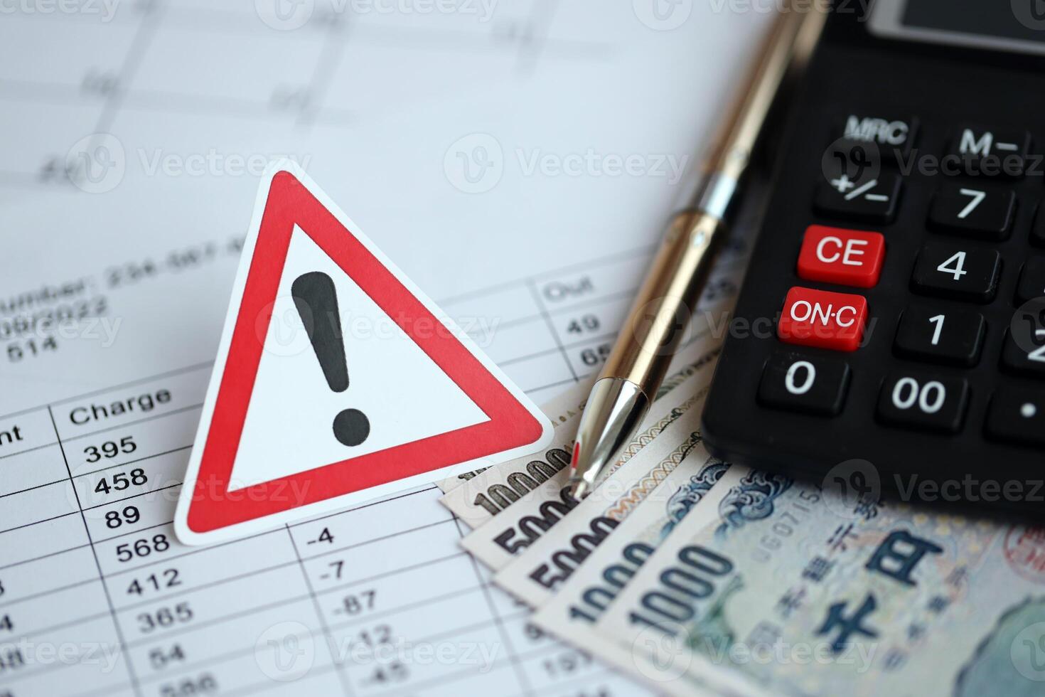 Exclamation sign and japanese tax calculations lies on table with calculator, pen and japanese yen photo
