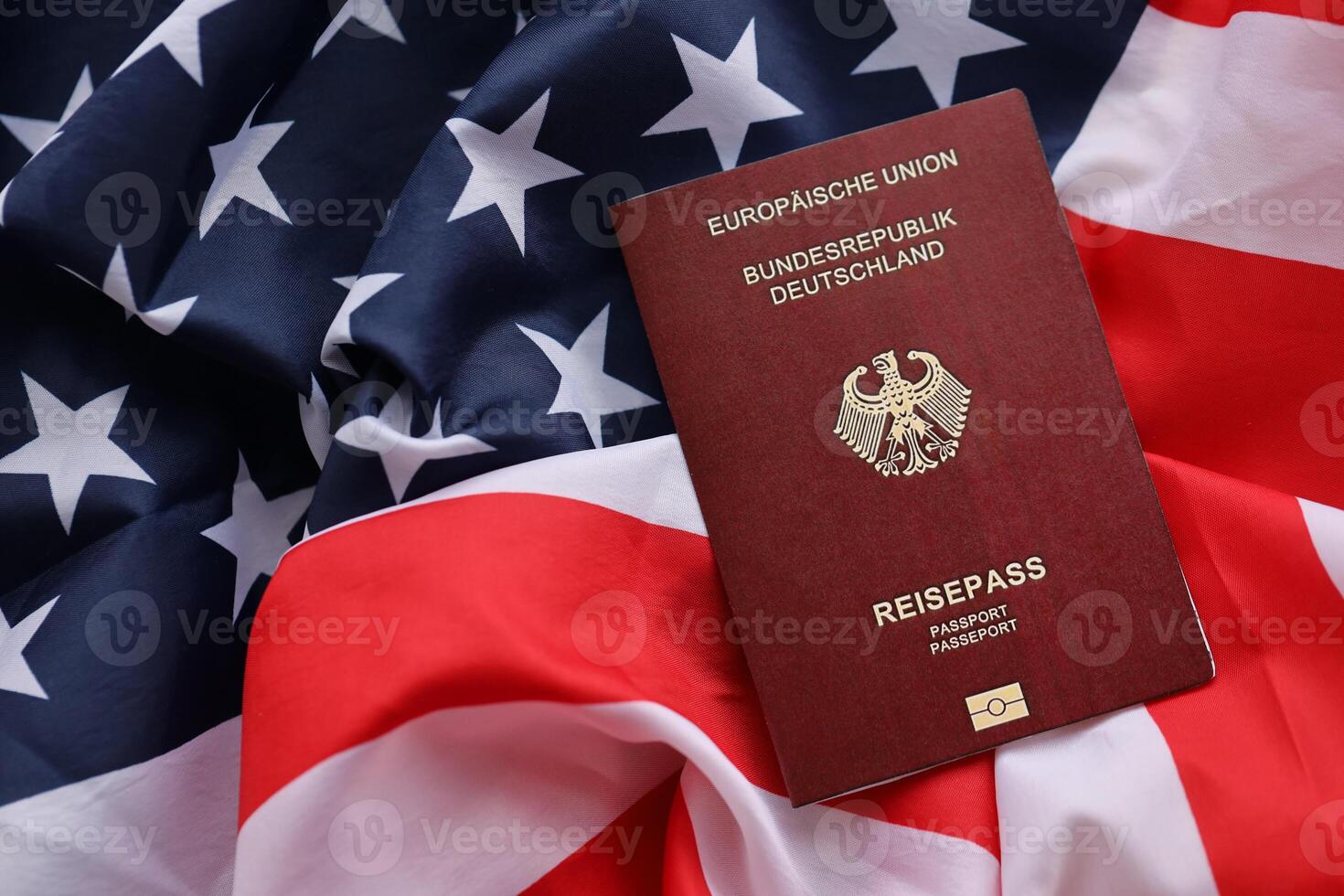 Red German passport of European Union on United States national flag background close up photo