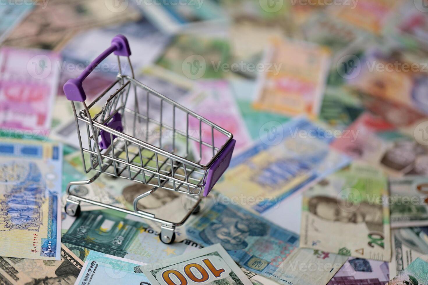 Supermarket trolley on many banknotes of different currency. Background of shopping worldwide photo