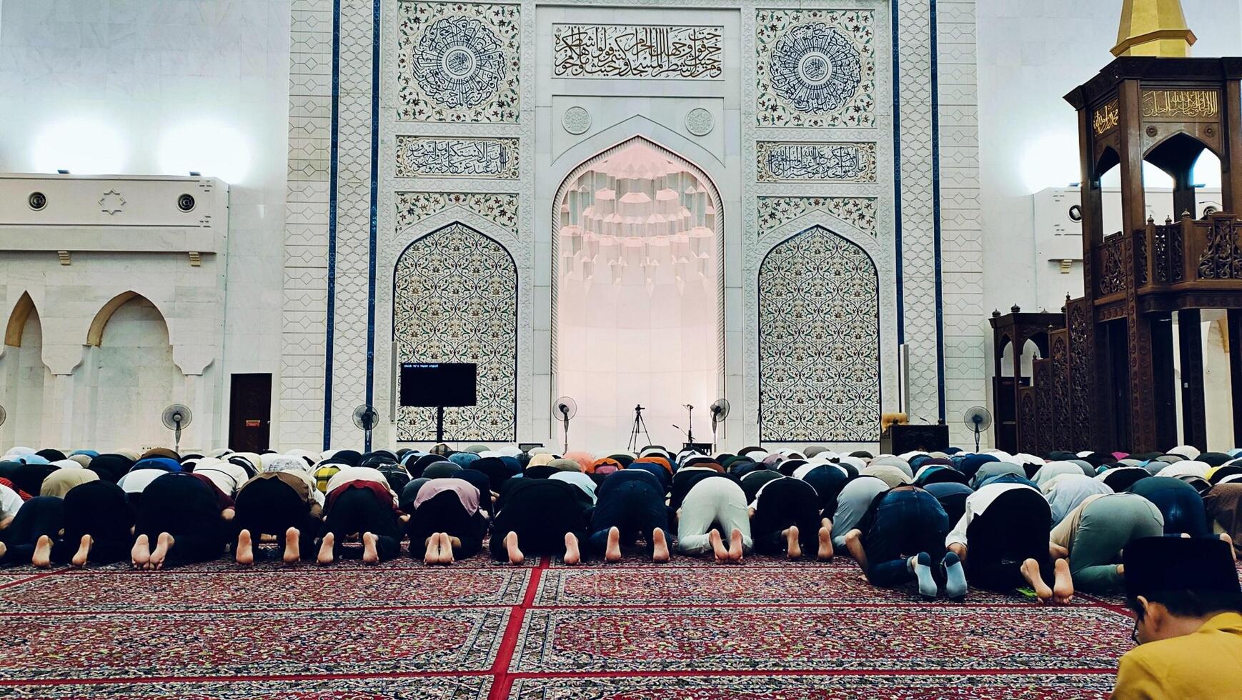In the quiet embrace of night, worshippers gather in the grand prayer hall of the mosque, seeking solace and connection through fervent prayers. photo
