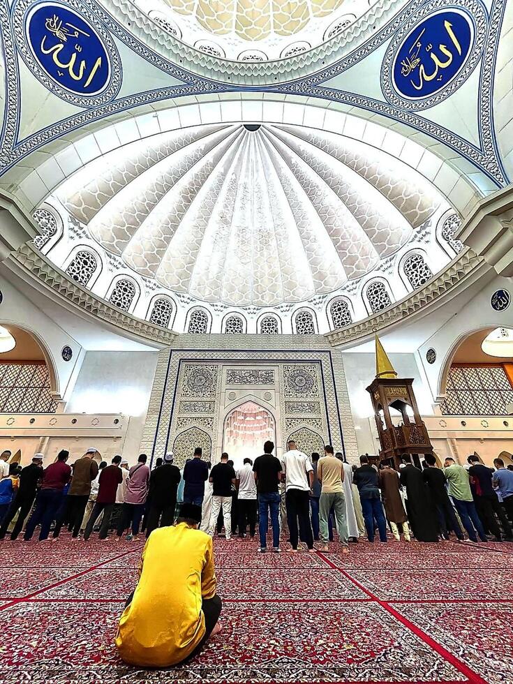 In the quiet embrace of night, worshippers gather in the grand prayer hall of the mosque, seeking solace and connection through fervent prayers. photo