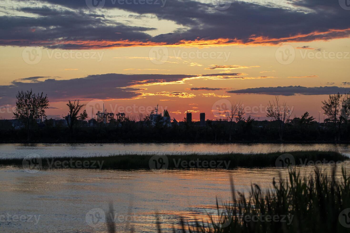 Silhouetted Cityscape at Sunset Over a Calm River, near Montreal photo