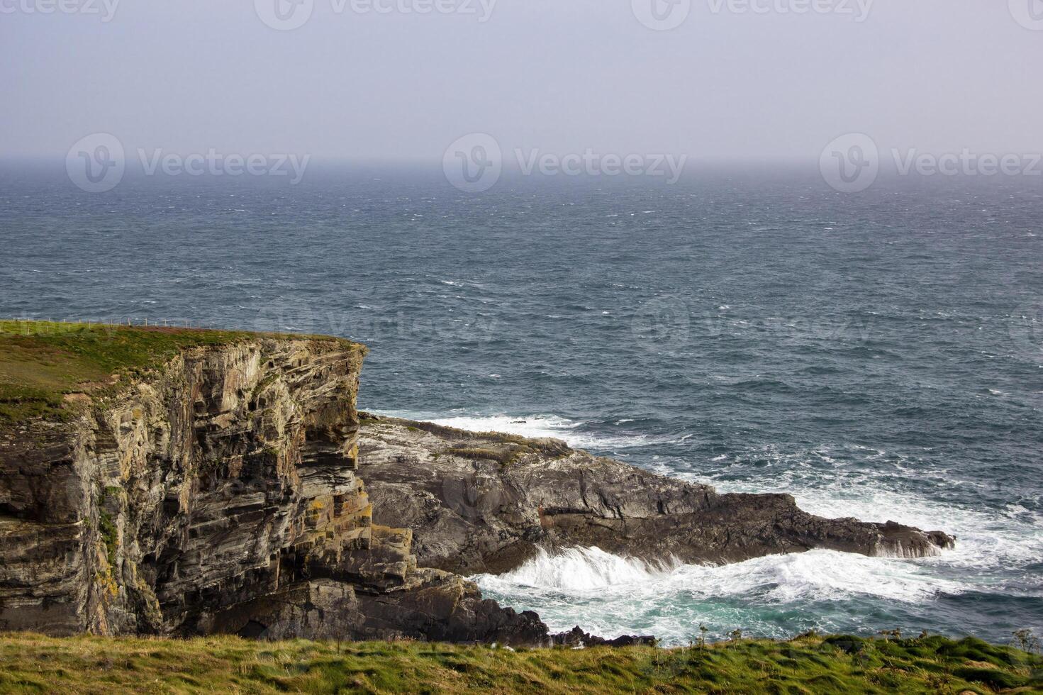 A Rugged Sea Cliff Along The Irish Coast On A Cloudy Day photo