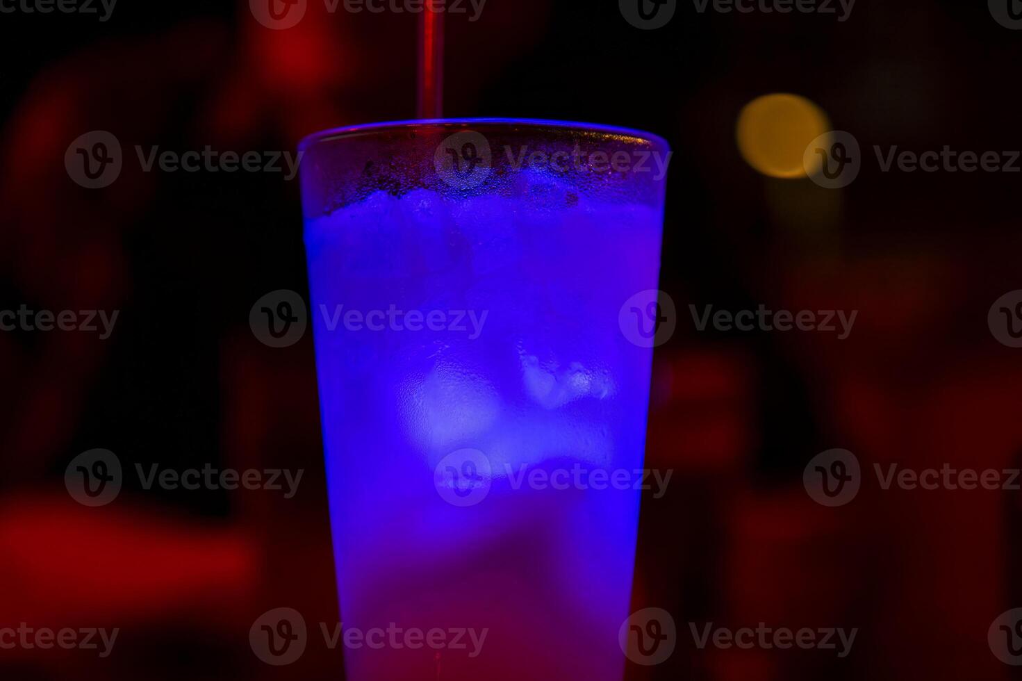 A Glass of Blue Drink With Ice in a Dark Bar photo