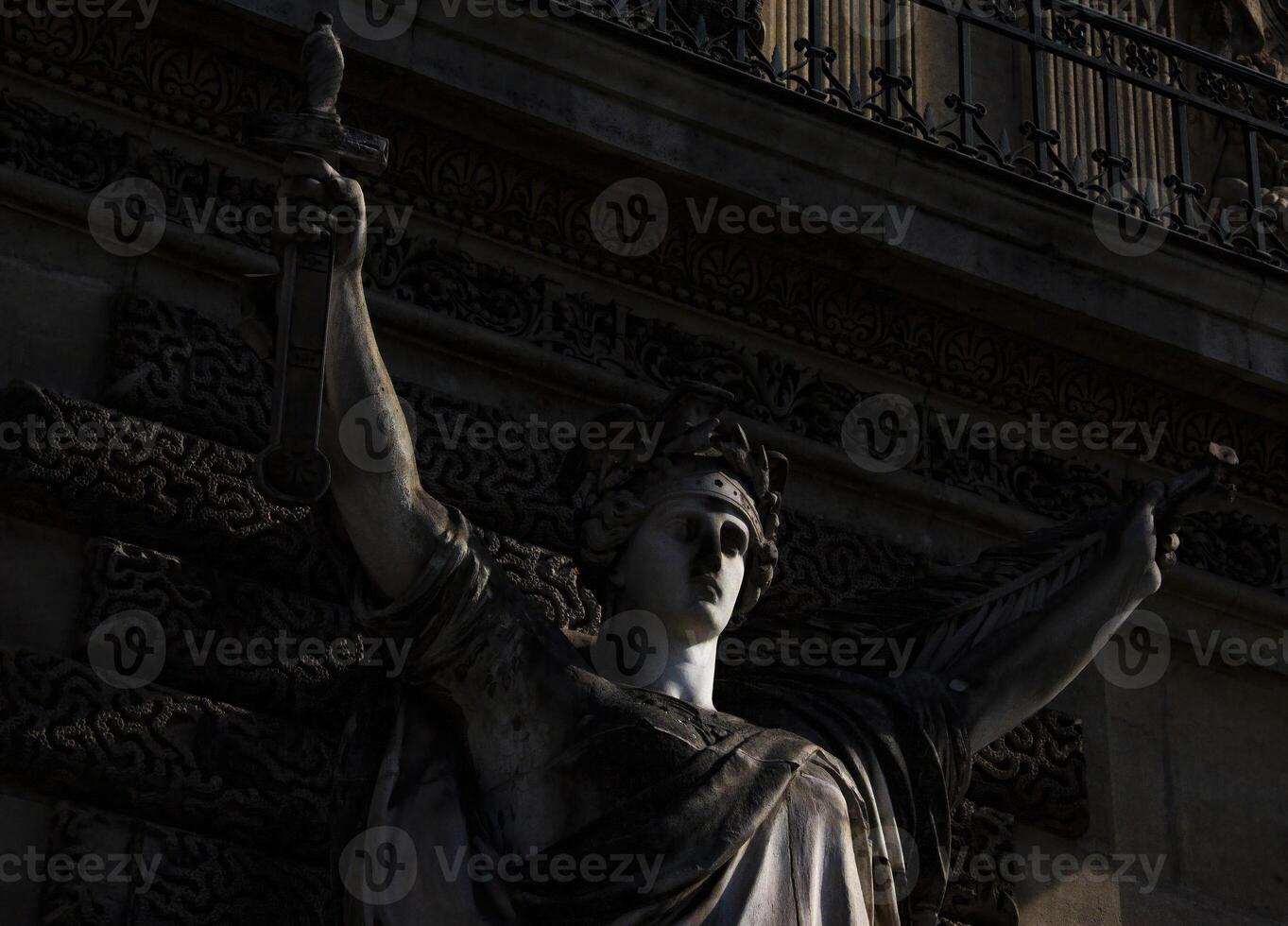 A Close-Up View of a Stone Statue Holding a Torch at Dusk in Paris, France photo